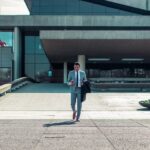 A businessman walking on an empty compound holding his phone.