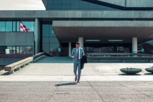 A businessman walking on an empty compound holding his phone.